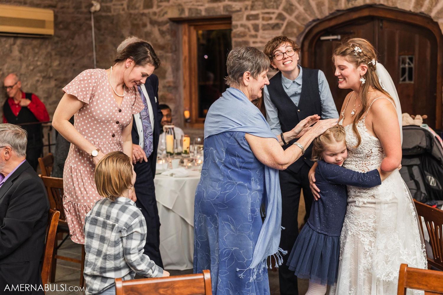 Wedding celebration in rustic stone venue with guests dancing and mingling on dance floor.