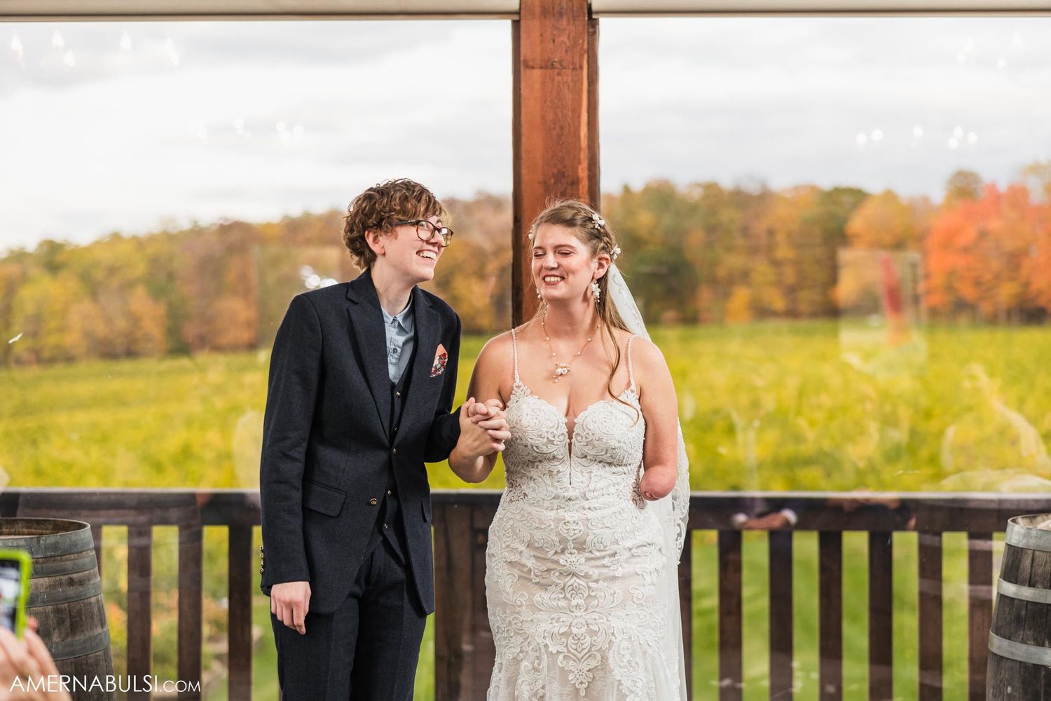 A couple shares an intimate moment on a deck overlooking autumn foliage in the countryside.