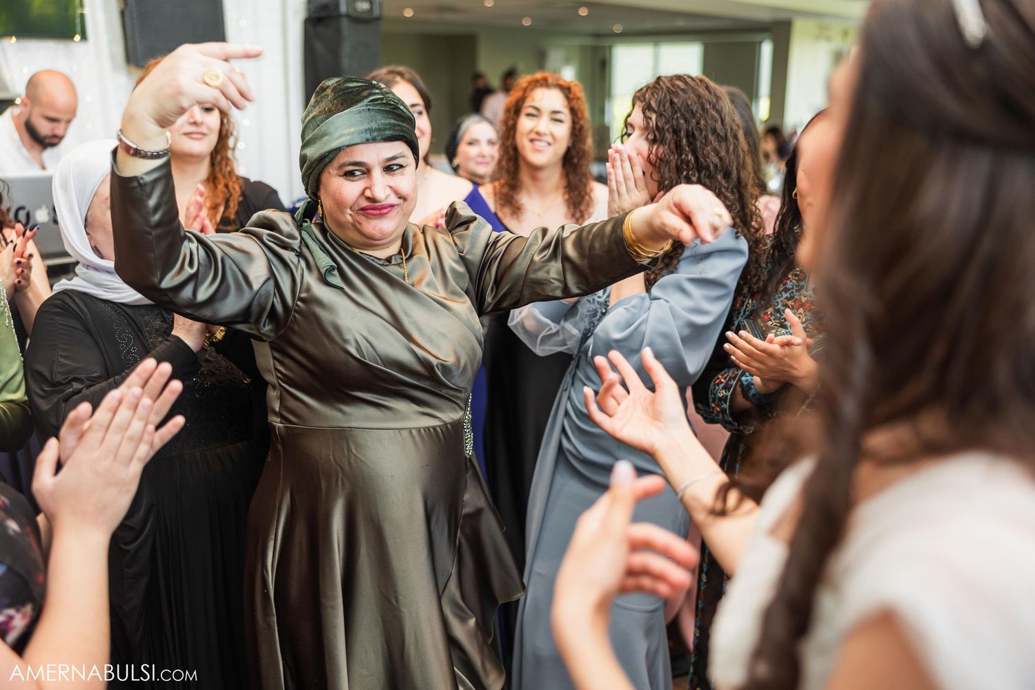 Wedding guests dancing joyfully in a circle at a lively celebration event with bright smiles and festive energy.
