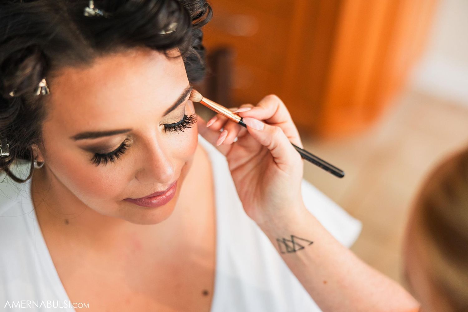 Close up of makeup being applied with a brush during wedding preparations.