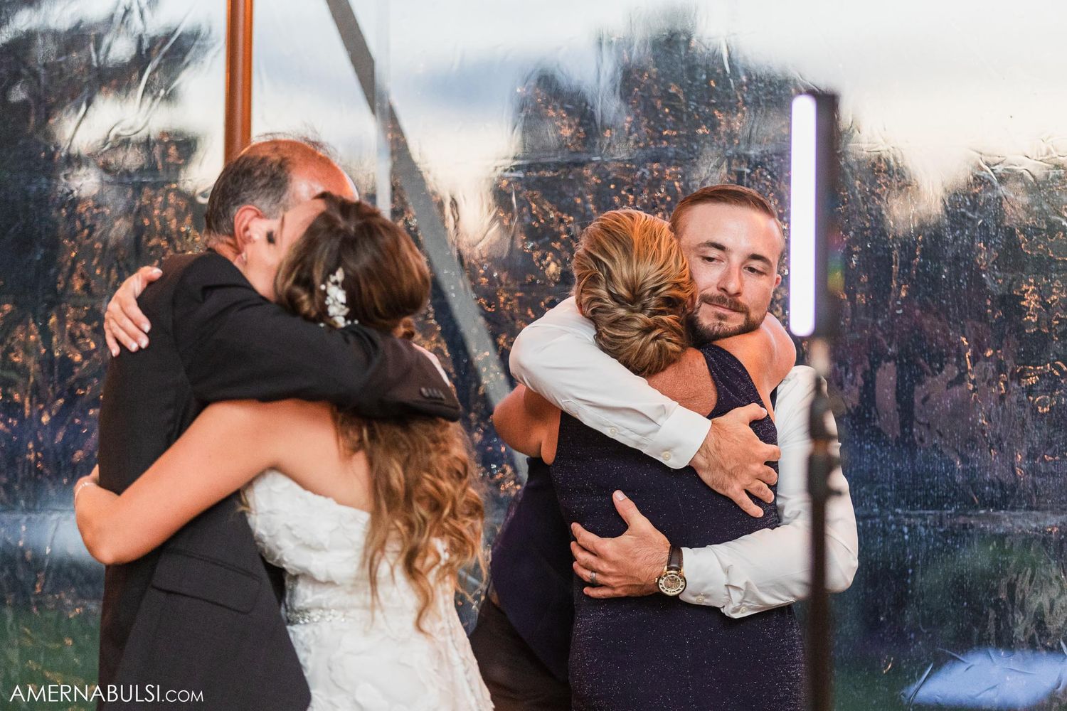Emotional group hugs are shared during a wedding reception celebration.