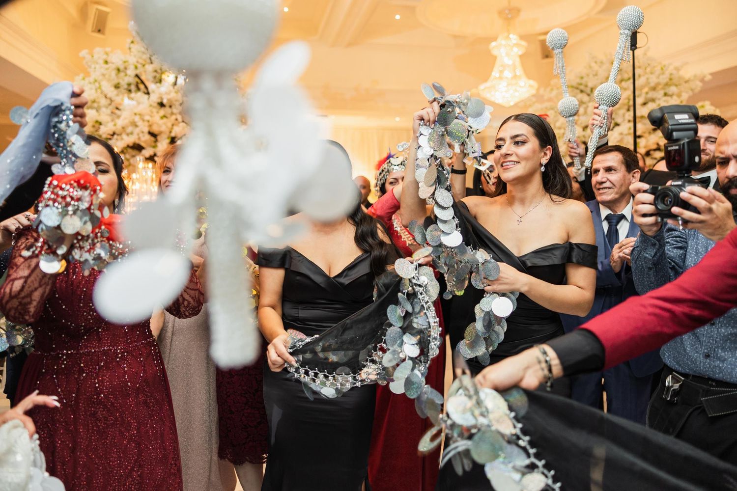 Wedding celebration with guests spraying silver party decorations in an elegant venue.