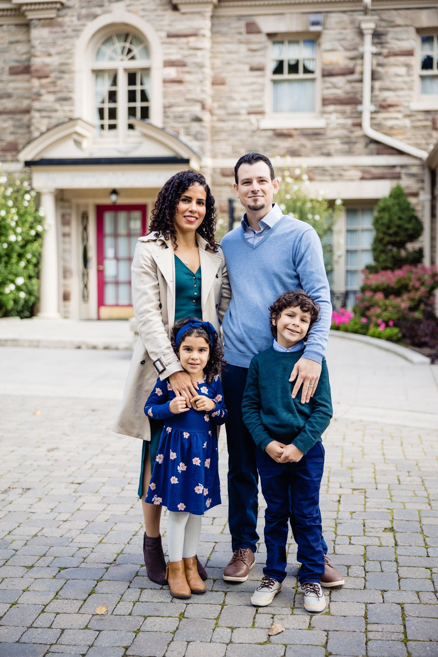 A family portrait in front of a historic stone building with arched windows.