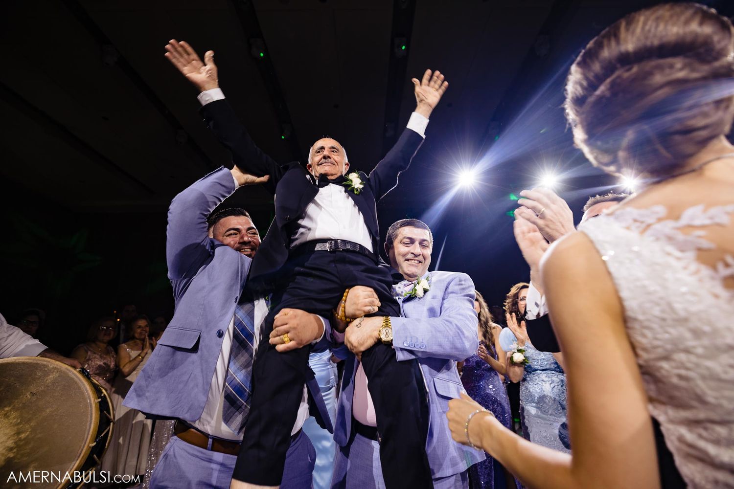 Wedding guests lift someone up during an energetic dance floor celebration.