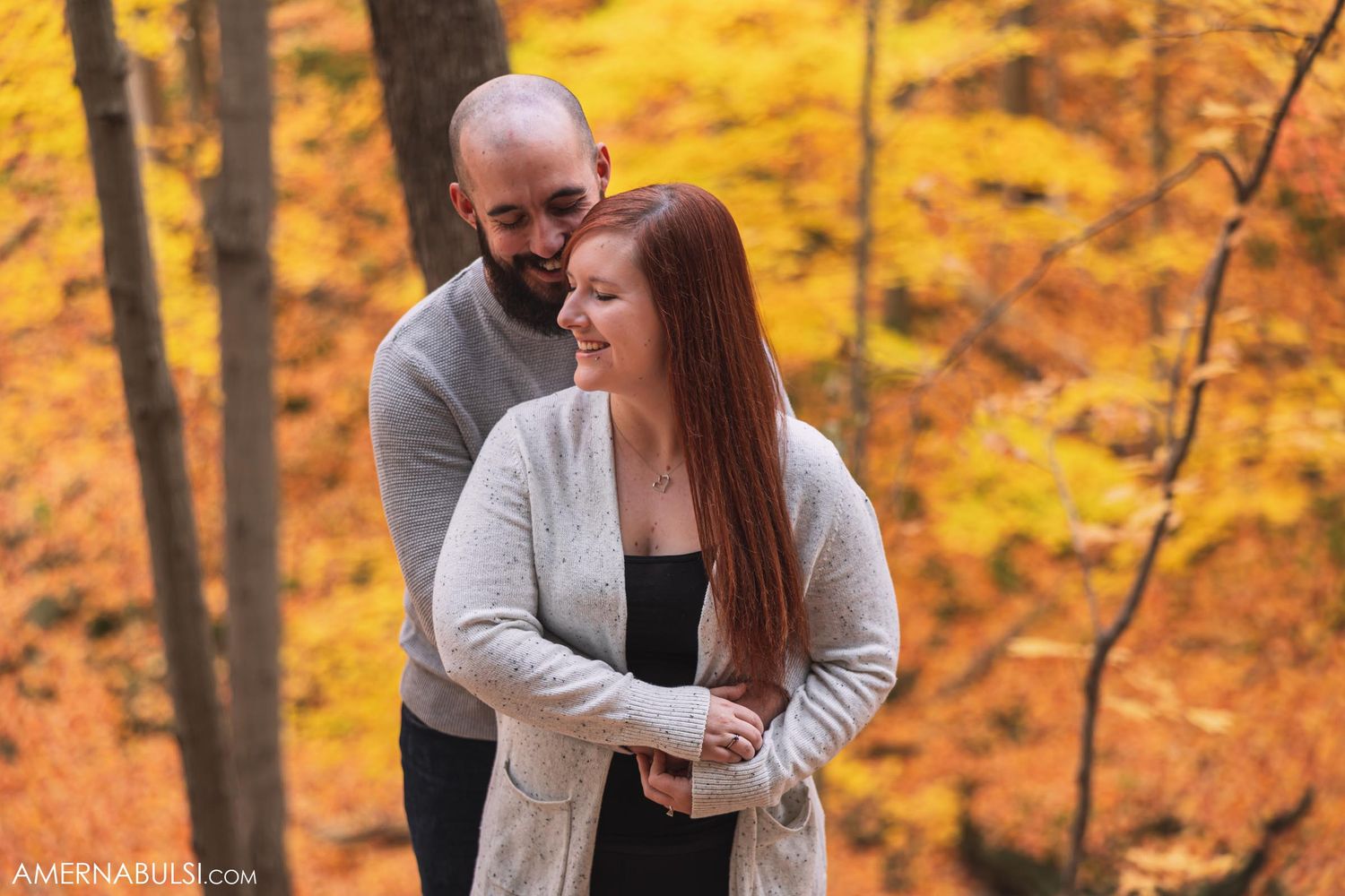 Couple shares tender moment amid golden fall foliage.