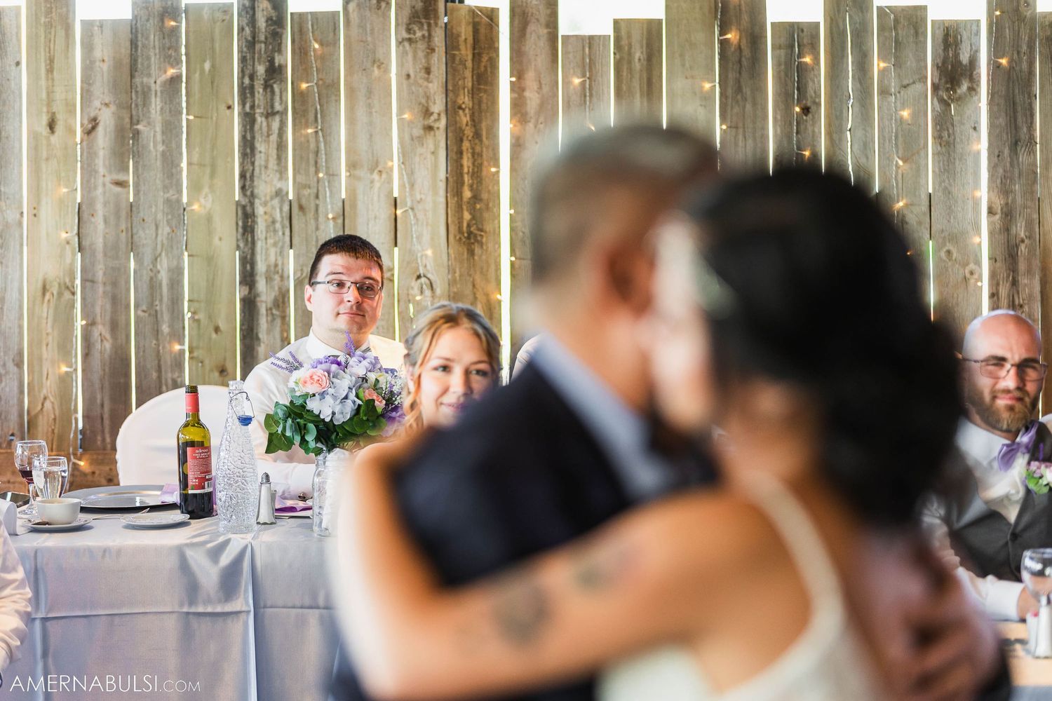 Wedding guests watch couple's first dance from decorated reception tables.