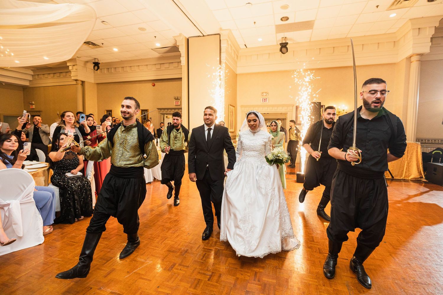 Traditional wedding celebration with guests dancing in a grand ballroom.