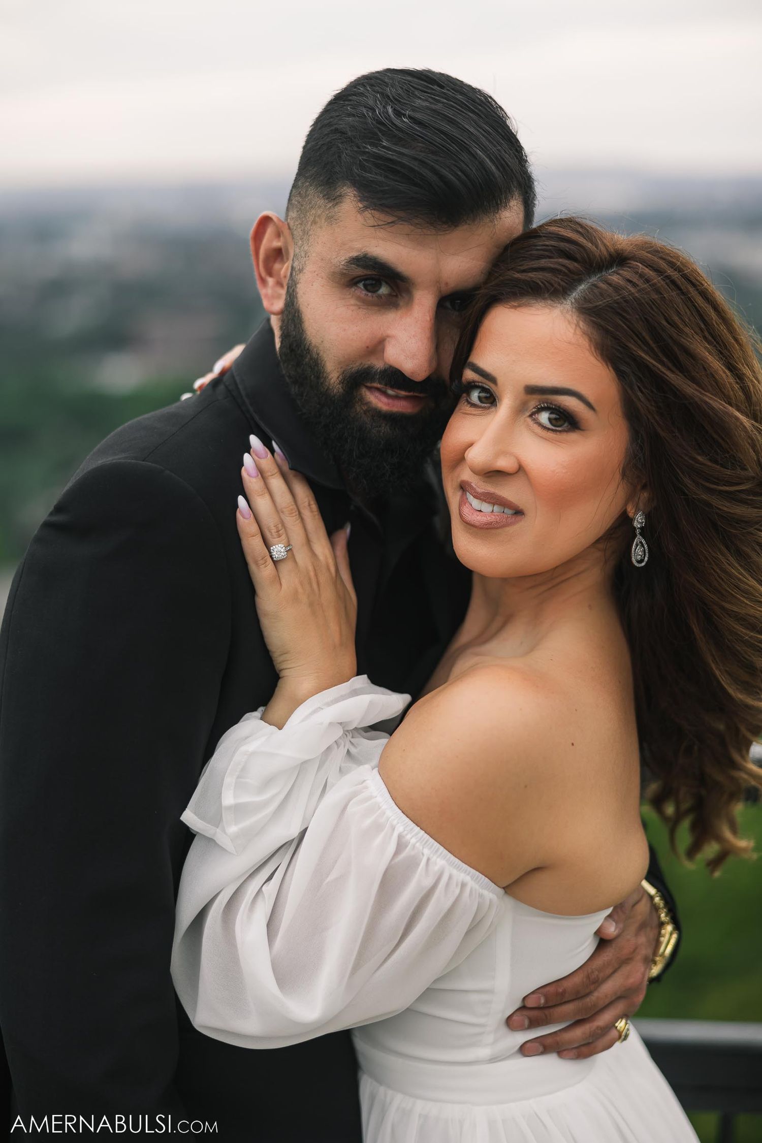 Romantic couple posing together at scenic overlook during engagement photoshoot.