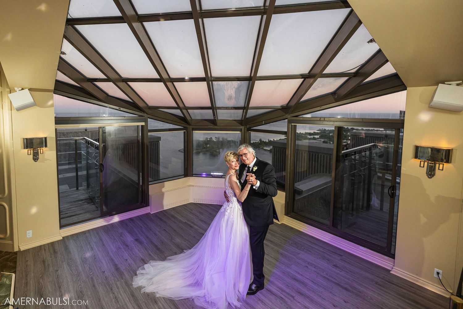 A couple dances in an elegant glass-ceiling room with purple lighting.