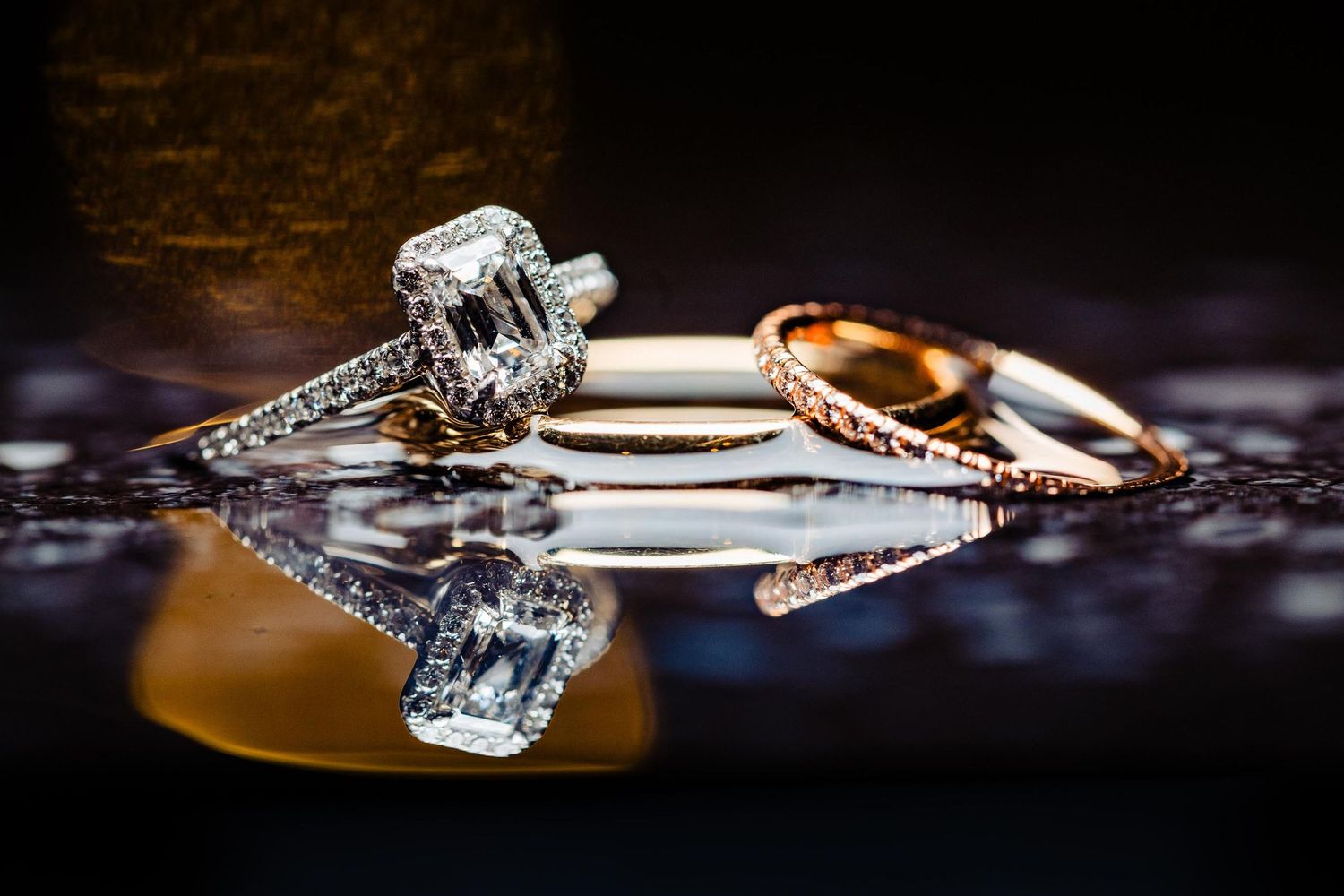 Wedding rings with diamonds photographed with dramatic lighting and reflection.