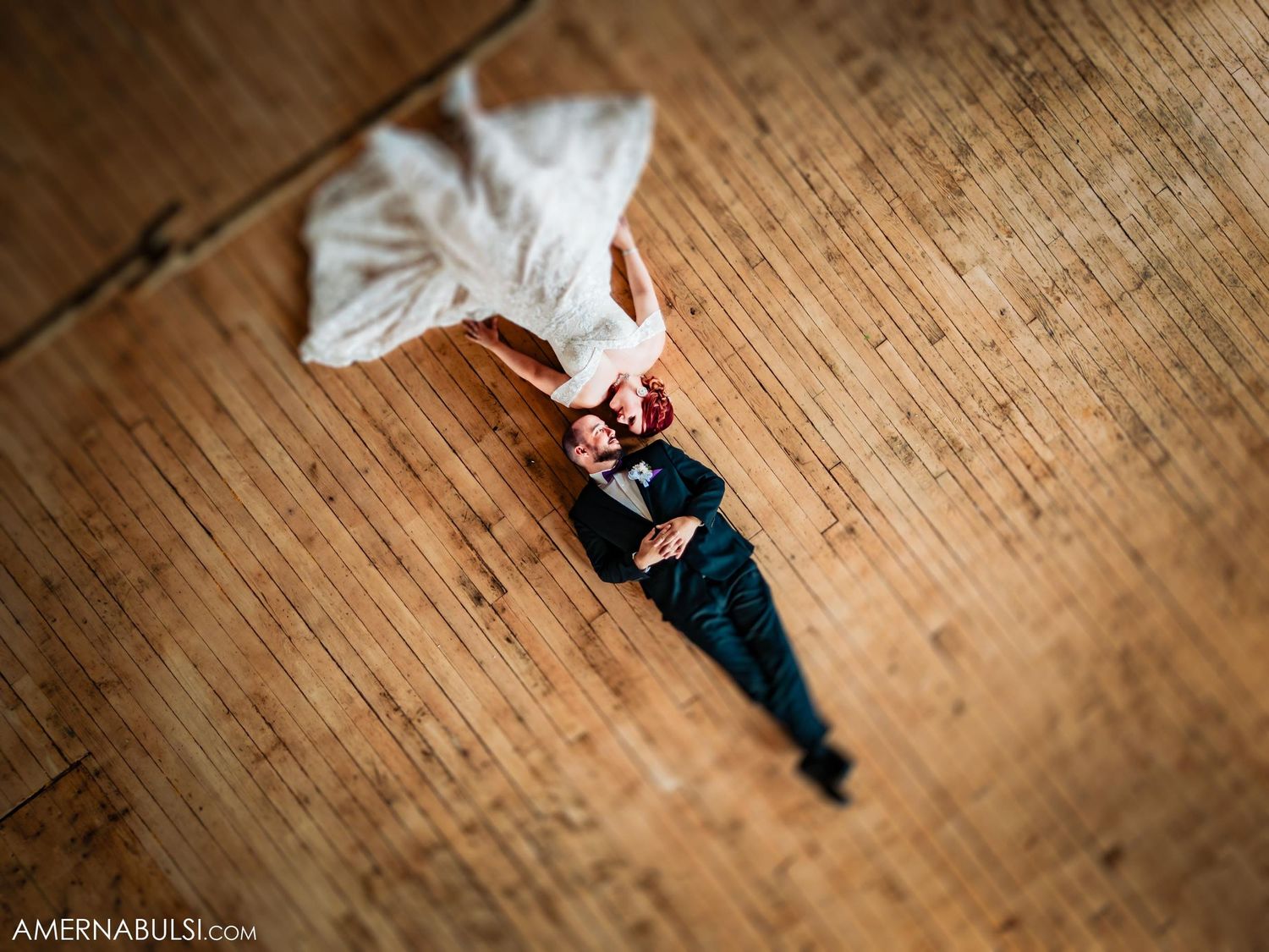 Artistic overhead shot of someone lying on wooden flooring in formal attire.