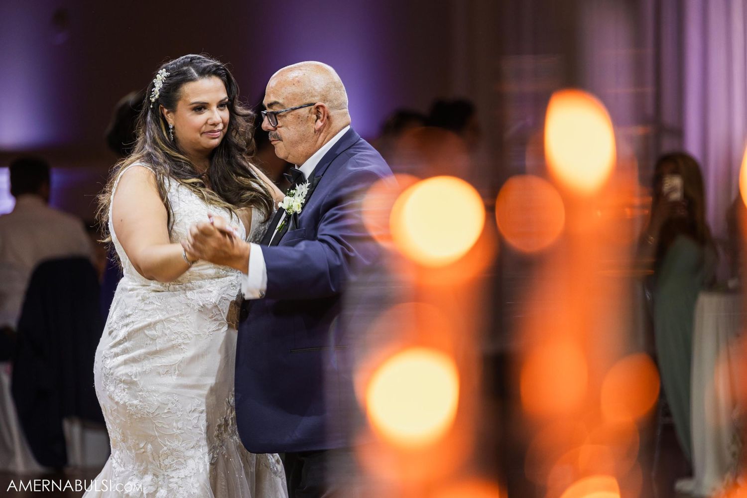 A wedding dance moment captured with ambient bokeh lights creating a romantic atmosphere.