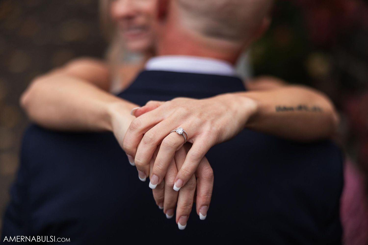 Close-up of bride's hands showing wedding ring while embracing.