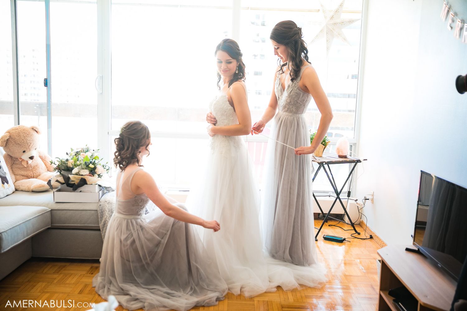 Getting ready scene with bridesmaids in soft natural window light.