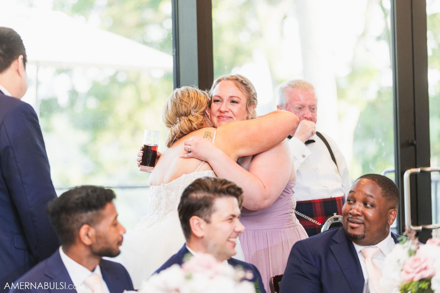 Wedding guests share warm embraces during an emotional moment at the reception.