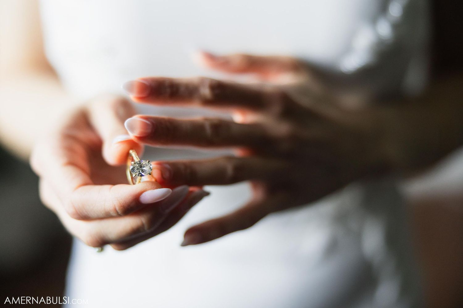 Close-up shot of hands holding an elegant engagement ring in natural light.