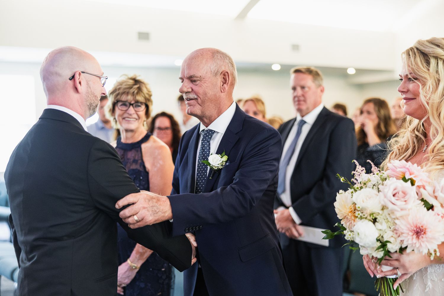 Wedding scene with guests hugging and showing emotion during celebration at an elegant indoor reception.