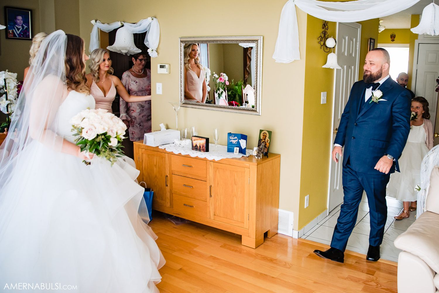 A bride in a flowing white wedding dress walks down a wooden hallway in a church or venue.