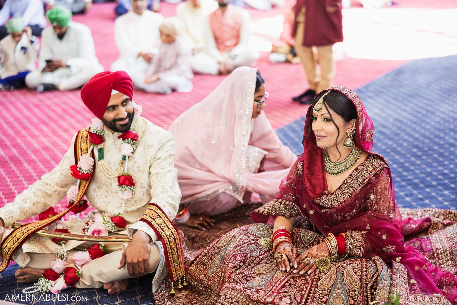 A traditional Sikh wedding ceremony with the couple seated on a red carpet during the Anand Karaj ceremony.