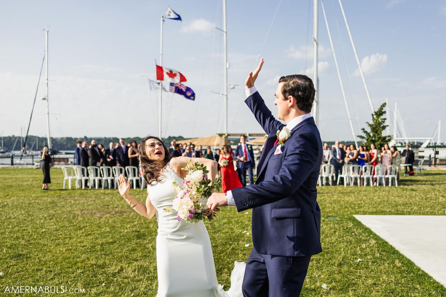 Wedding celebration with couple celebrating under Canadian and other flags flying at waterfront venue.