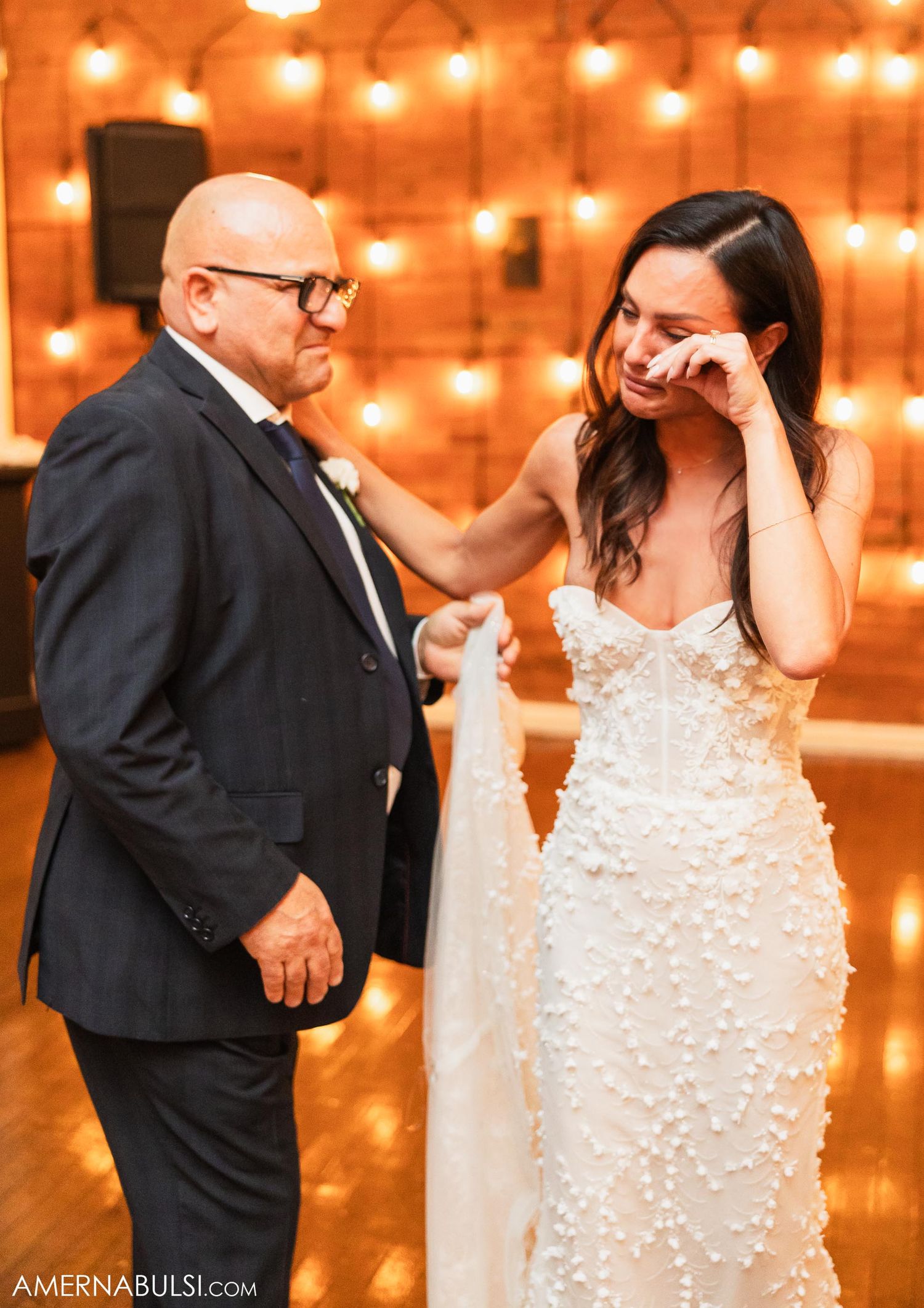 An emotional moment captured during a wedding with string lights creating a warm ambiance.
