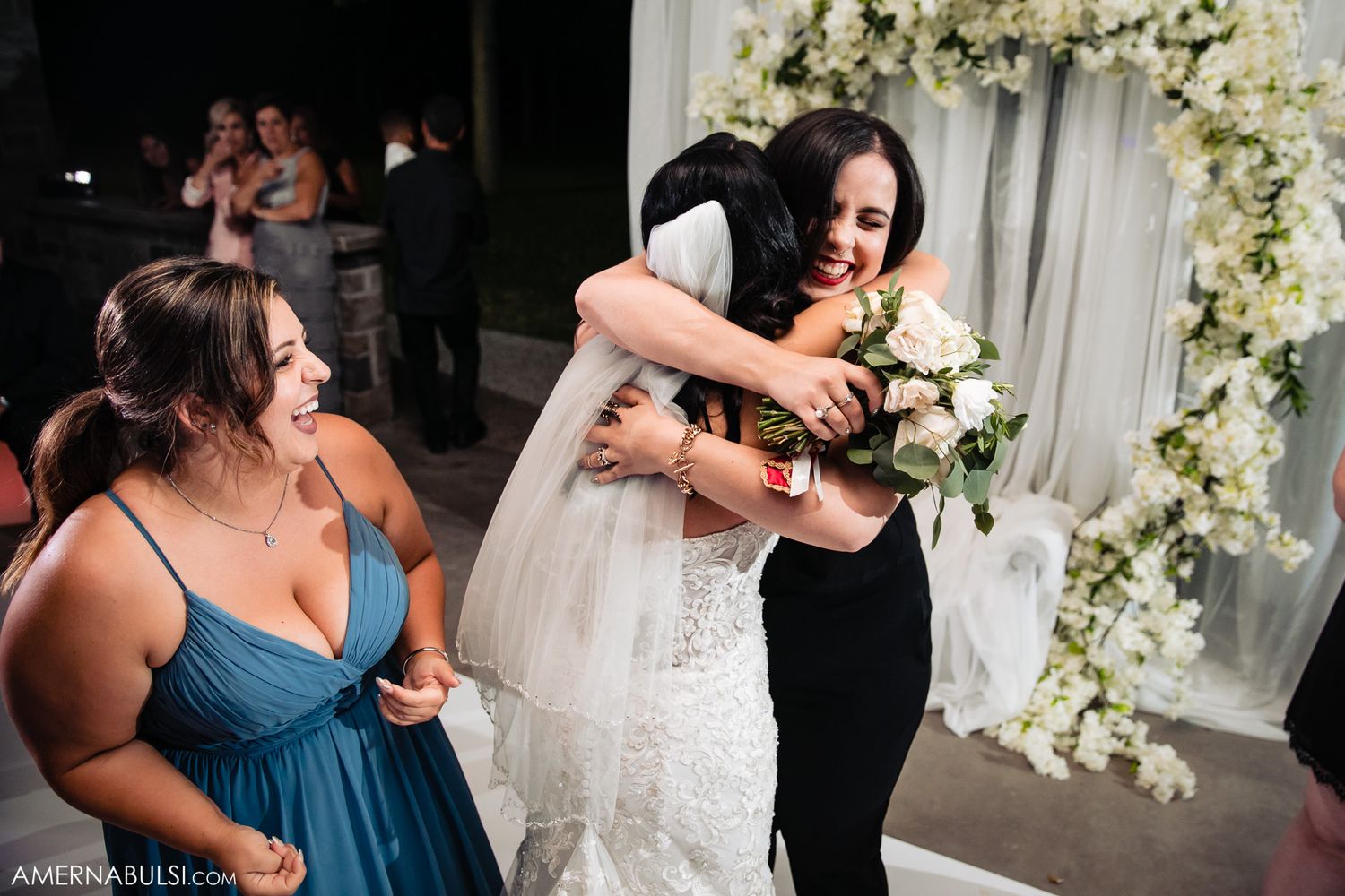 Wedding party members dance and celebrate together during a joyful reception with floral decorations.