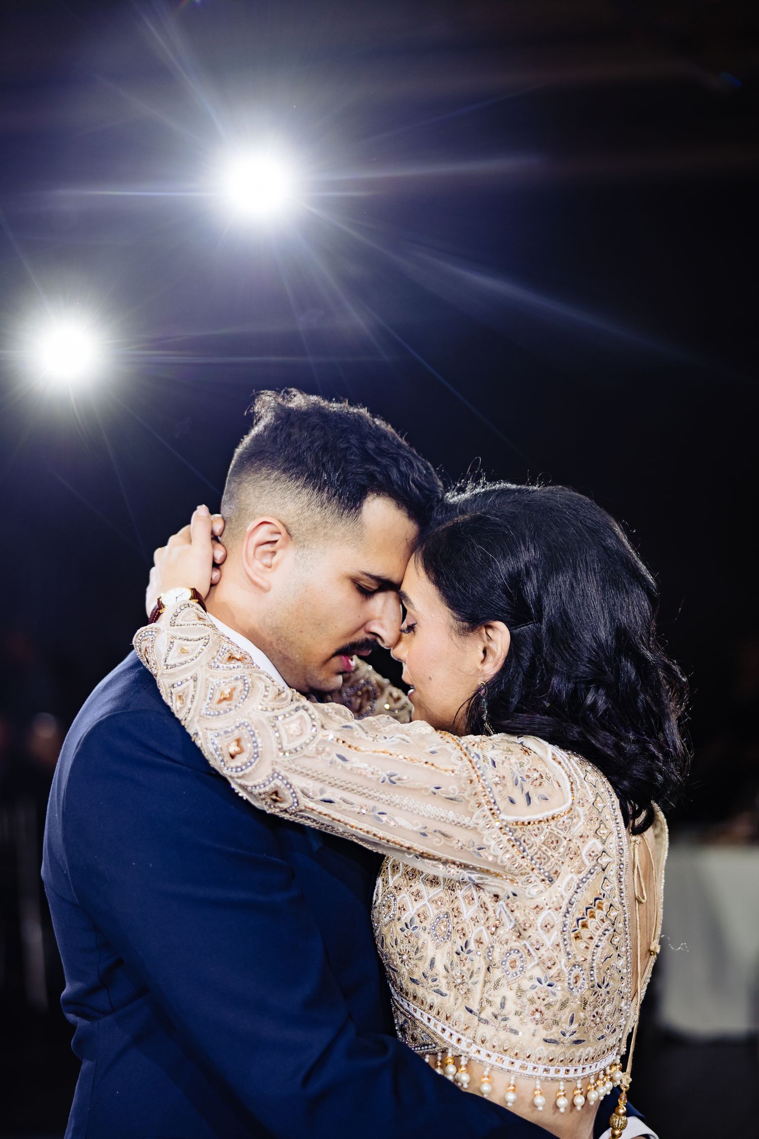 Couple shares an intimate dance moment under dramatic lighting at their wedding reception.