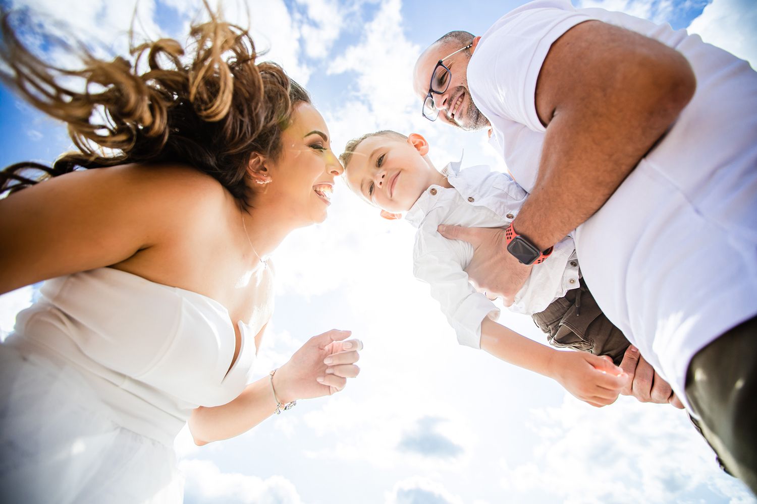A creative low-angle portrait of a group lying on grass against bright blue sky.