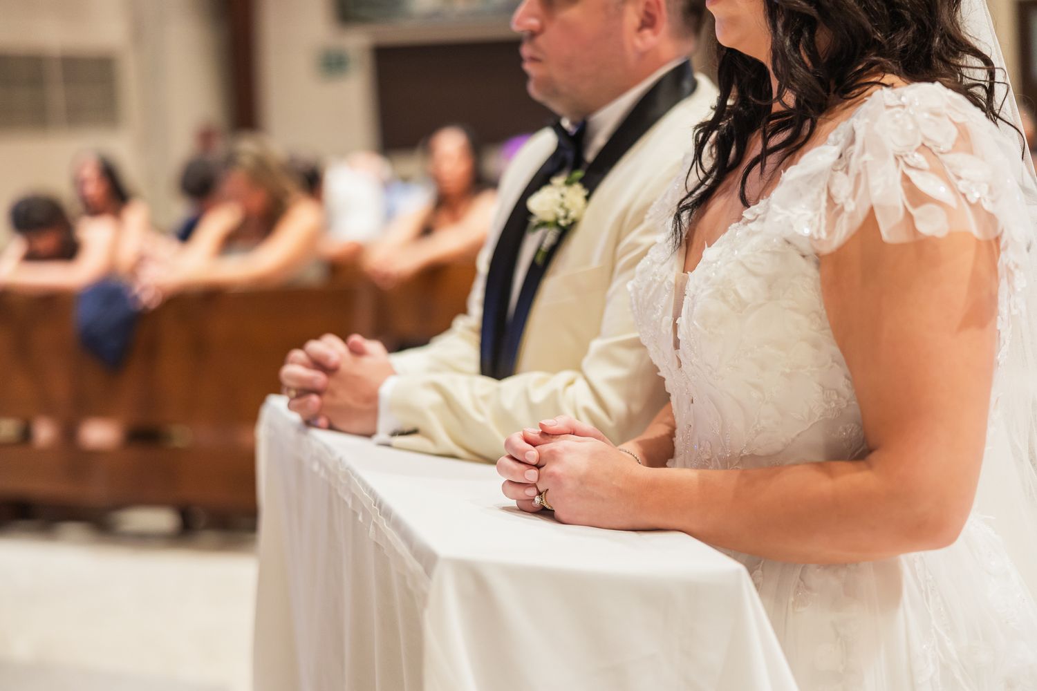 Bride and groom kneel in prayer together at the altar during their church wedding ceremony.