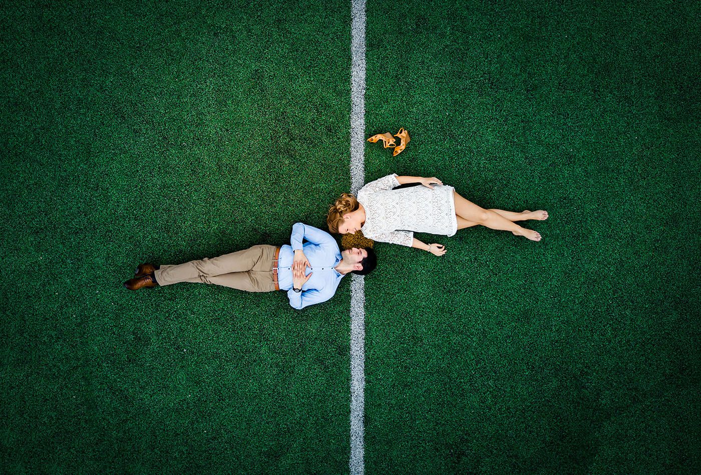People lying on green turf creating artistic aerial patterns.