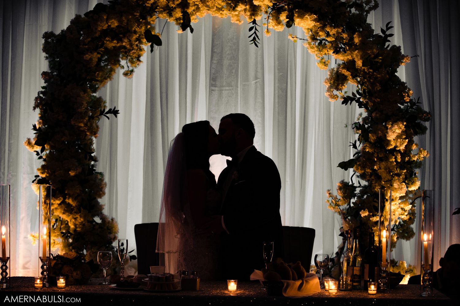 Wedding reception venue decorated with elegant floral arches and warm lighting creating a romantic atmosphere.
