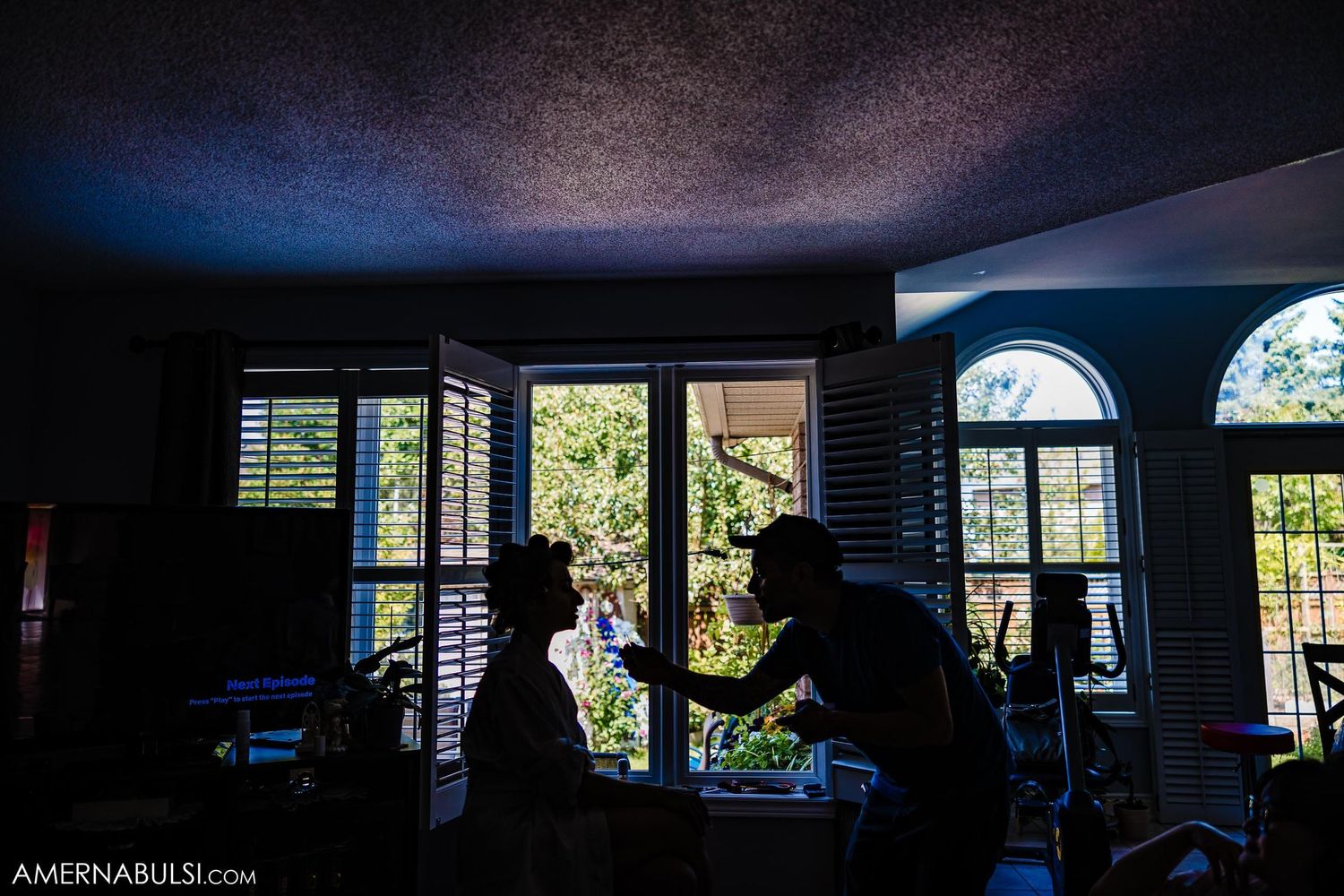 A silhouetted scene against bright windows showing preparation activities indoors.