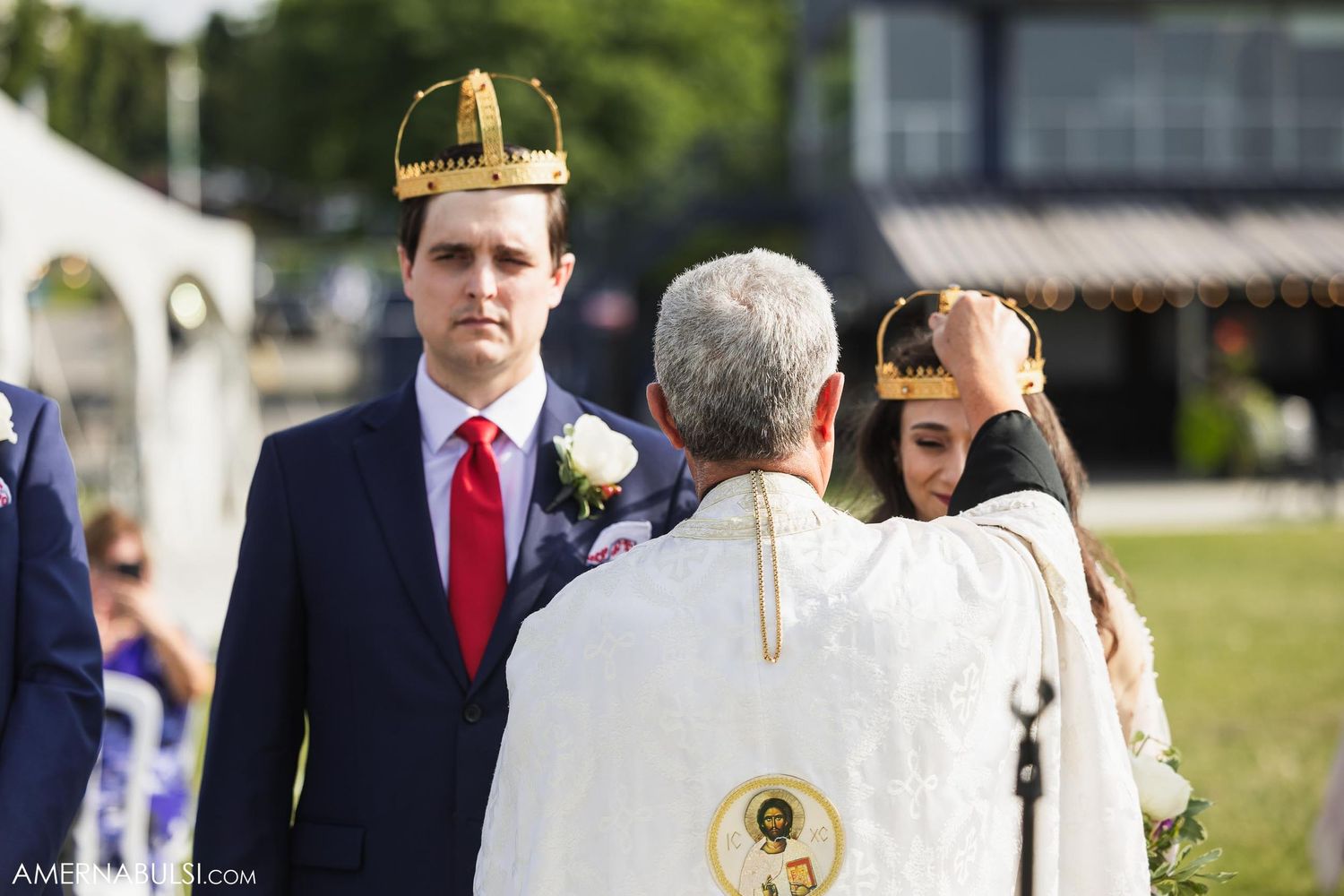 Wedding ceremony moment with officiant in traditional religious attire outdoors.
