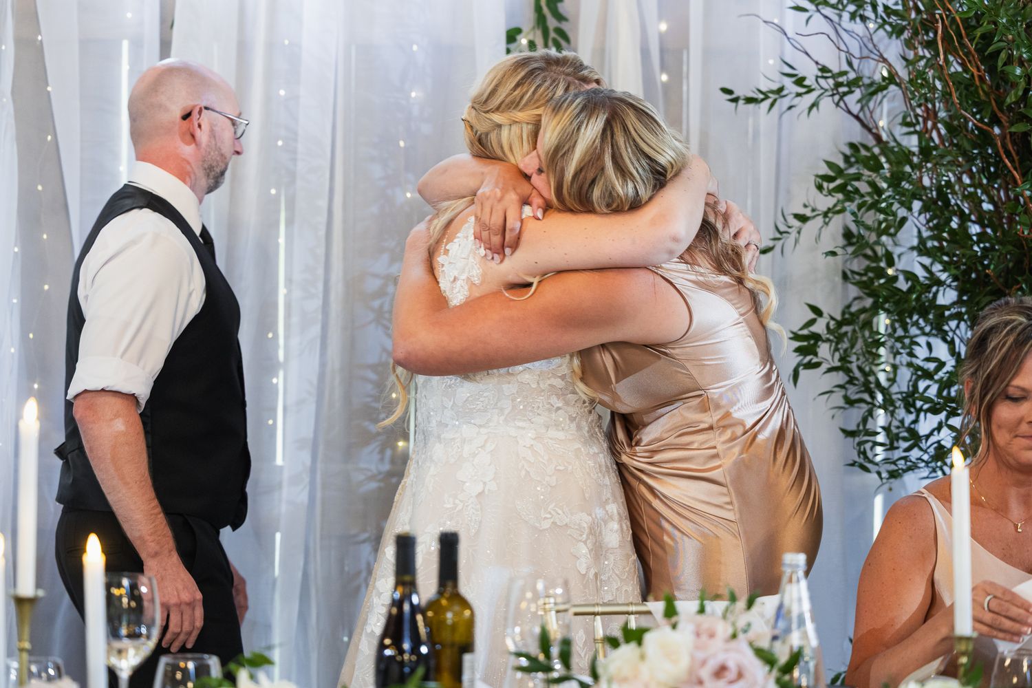 Emotional wedding reception moment with guests embracing during celebrations.