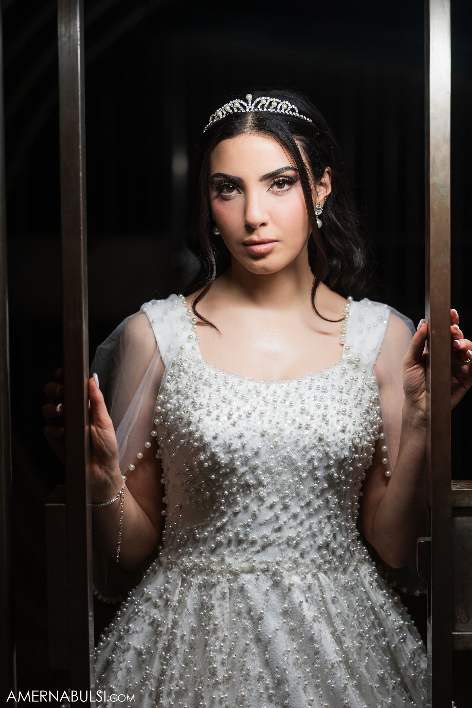 A close-up portrait of a bride wearing a crystal-embellished wedding dress and delicate tiara.