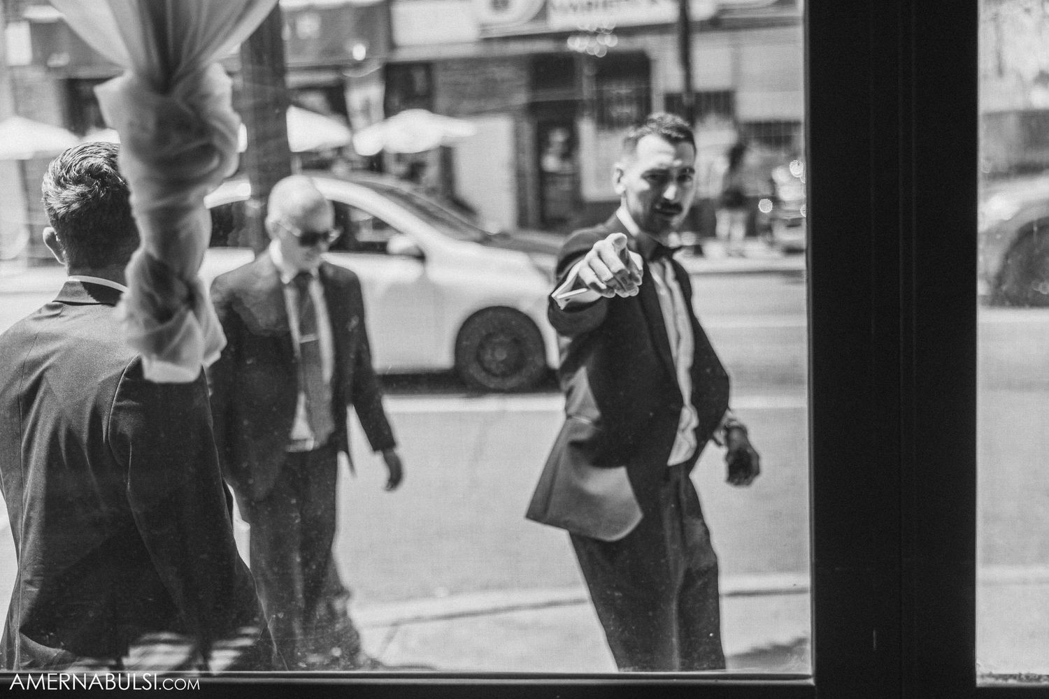 Black and white street photography captured through a window with urban scene outside.