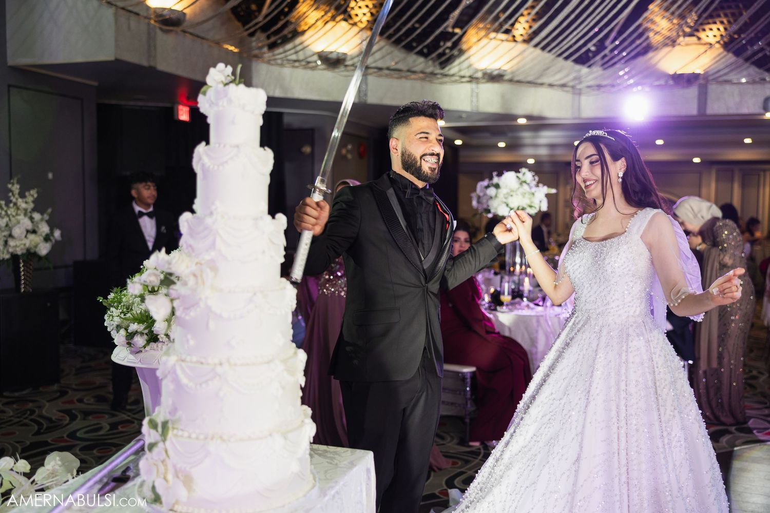 Elegant wedding celebration with white decor, floral arrangements and purple lighting effects.