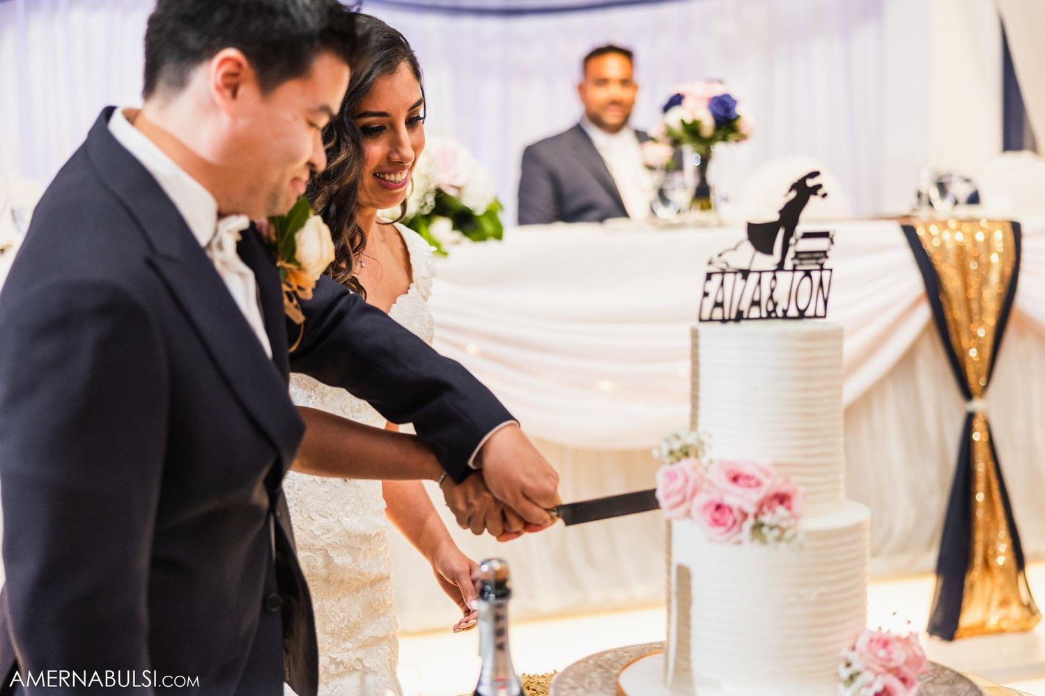 Newlyweds cut their elegant white wedding cake together at their reception.