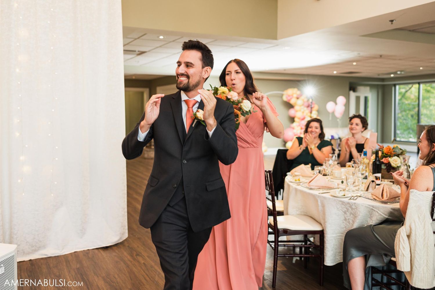 Excited wedding party members make joyful entrances at an elegant indoor reception venue.