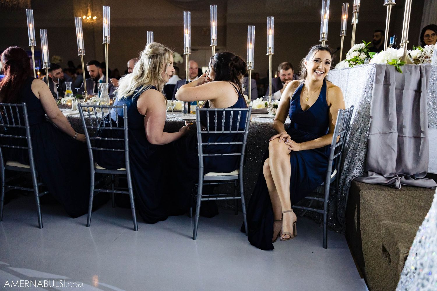 Wedding reception table setup with elegant candles and guests seated at formal dinner.