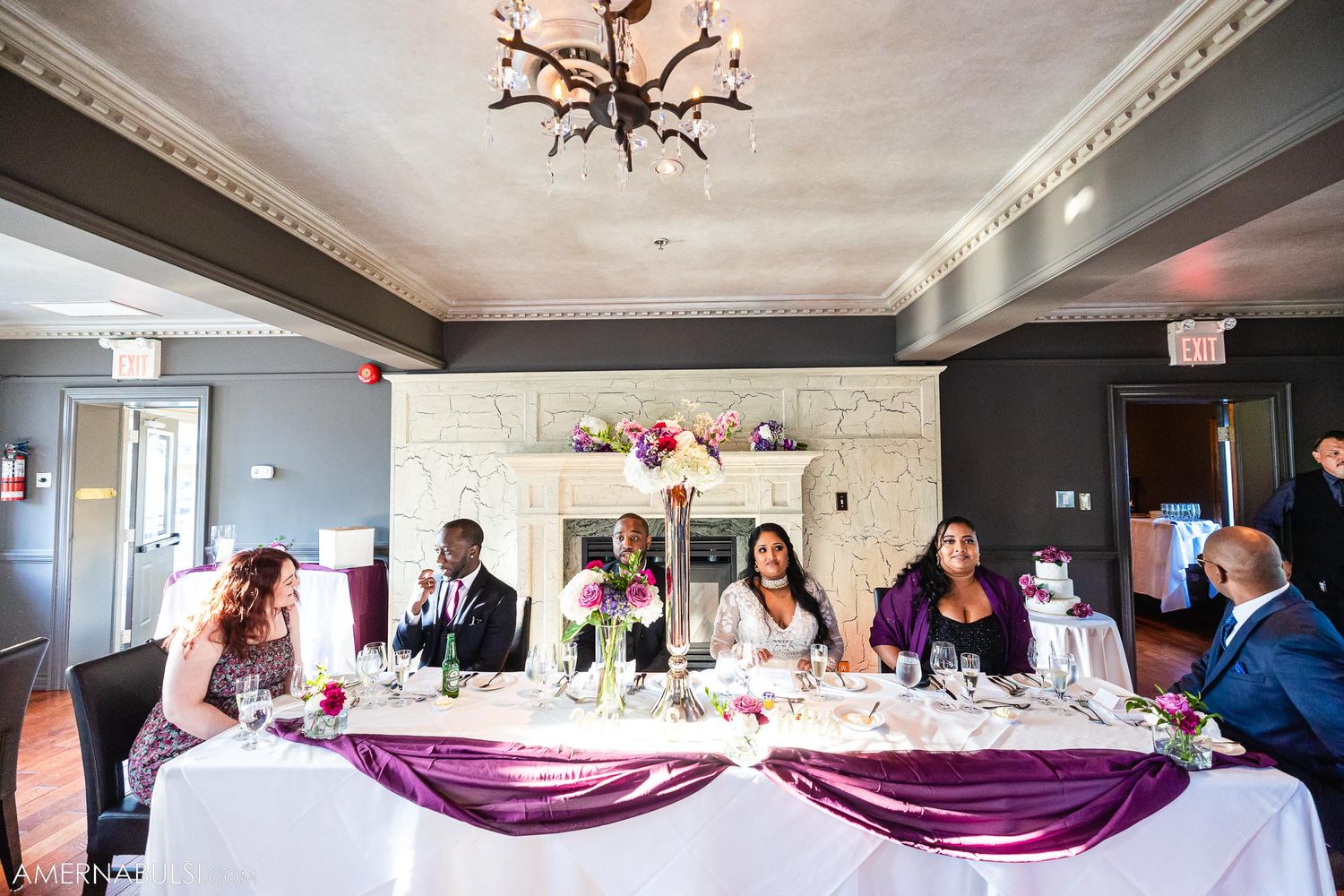 Wedding reception head table decorated with purple accents and elegant table settings.