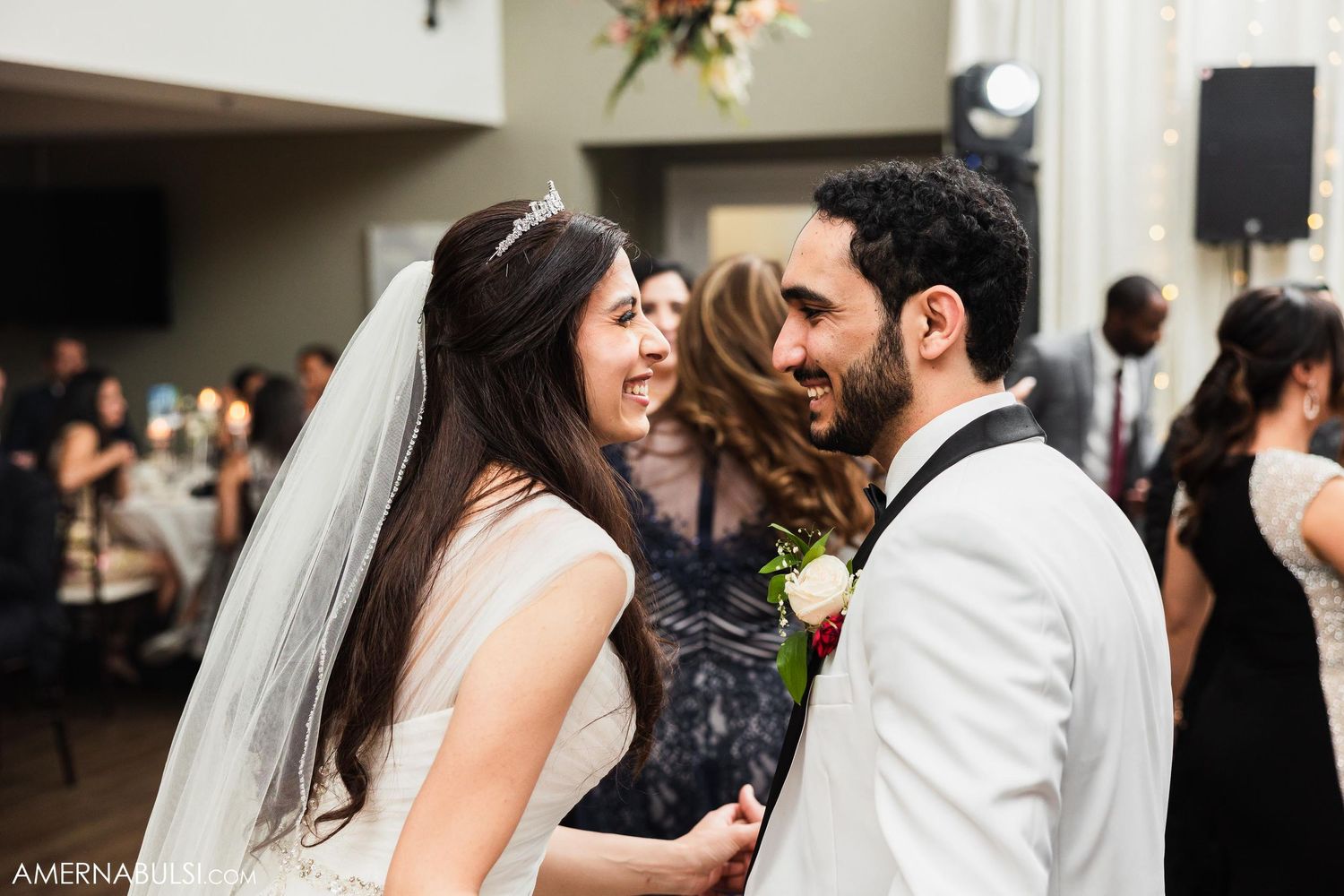 A joyful celebration moment between wedding guests at an indoor reception.