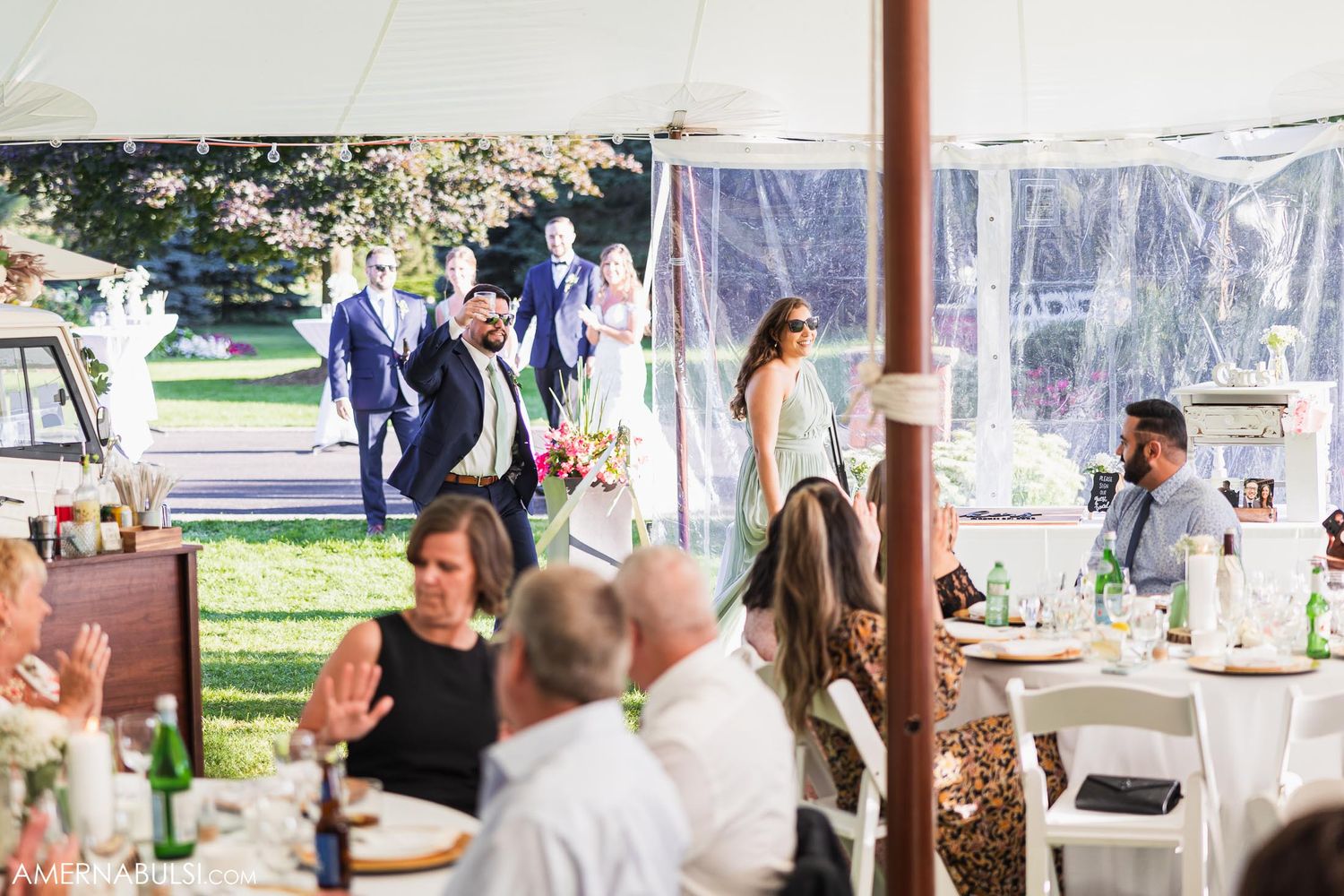 Guests seated at tables under an outdoor tent during a wedding reception.