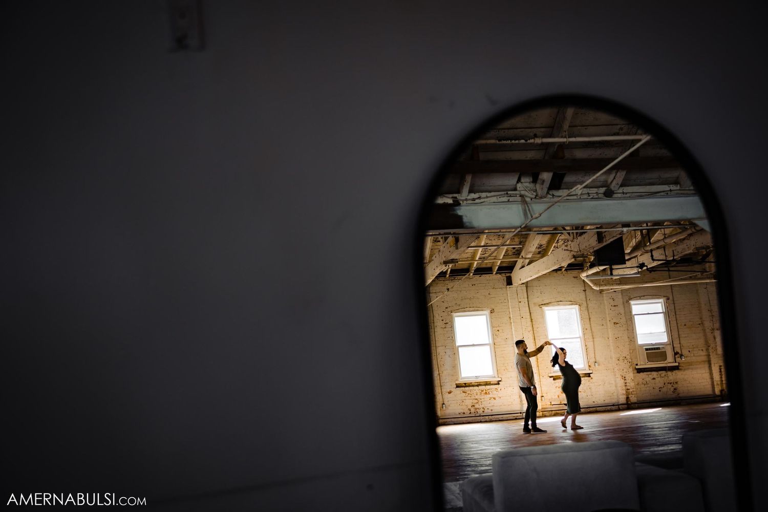 Silhouette of couple seen through arched doorway in industrial loft space.