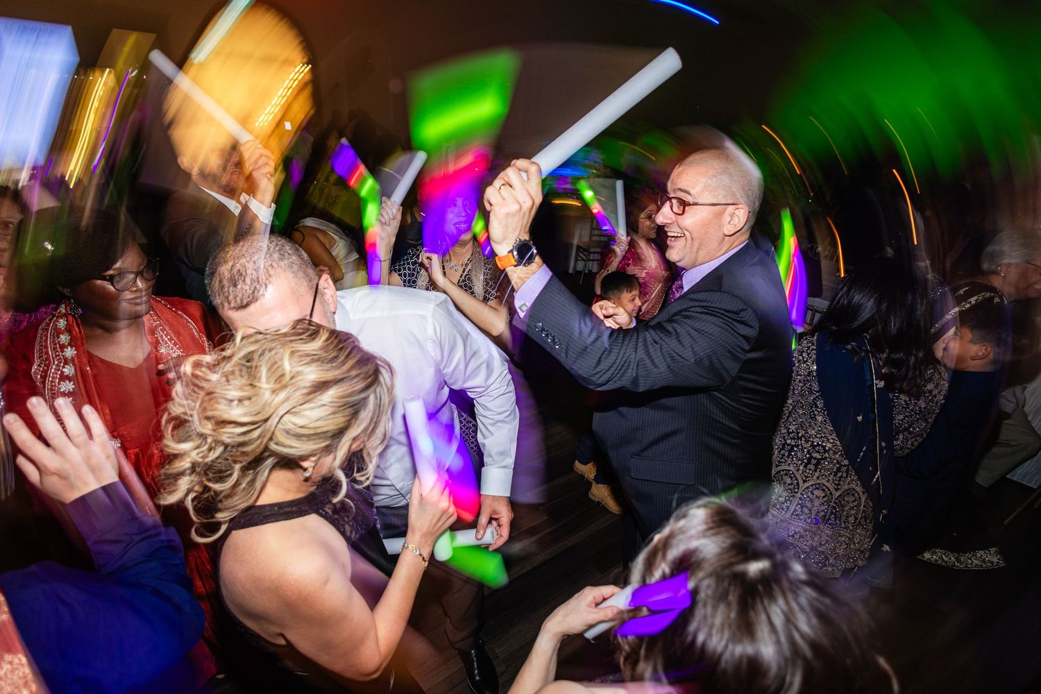 People dancing and celebrating at a nightclub with colorful lighting and disco atmosphere.