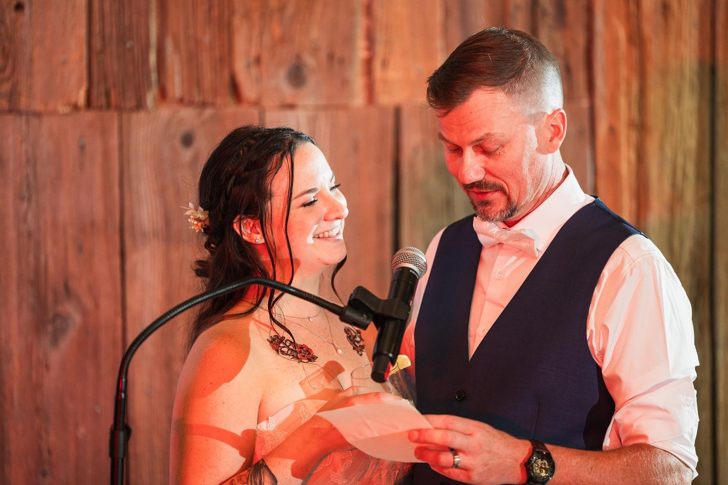 Couple sharing a moment while reading from papers in rustic barn setting.