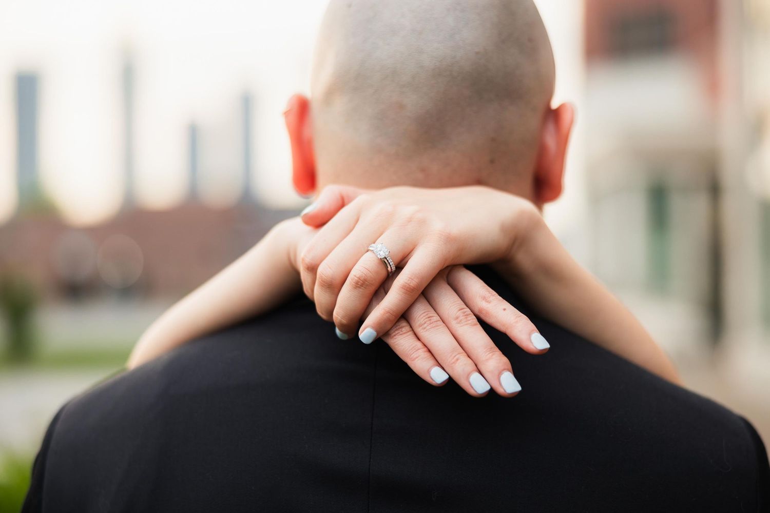 Close-up view of hands embracing on a person's shoulder during a wedding celebration.