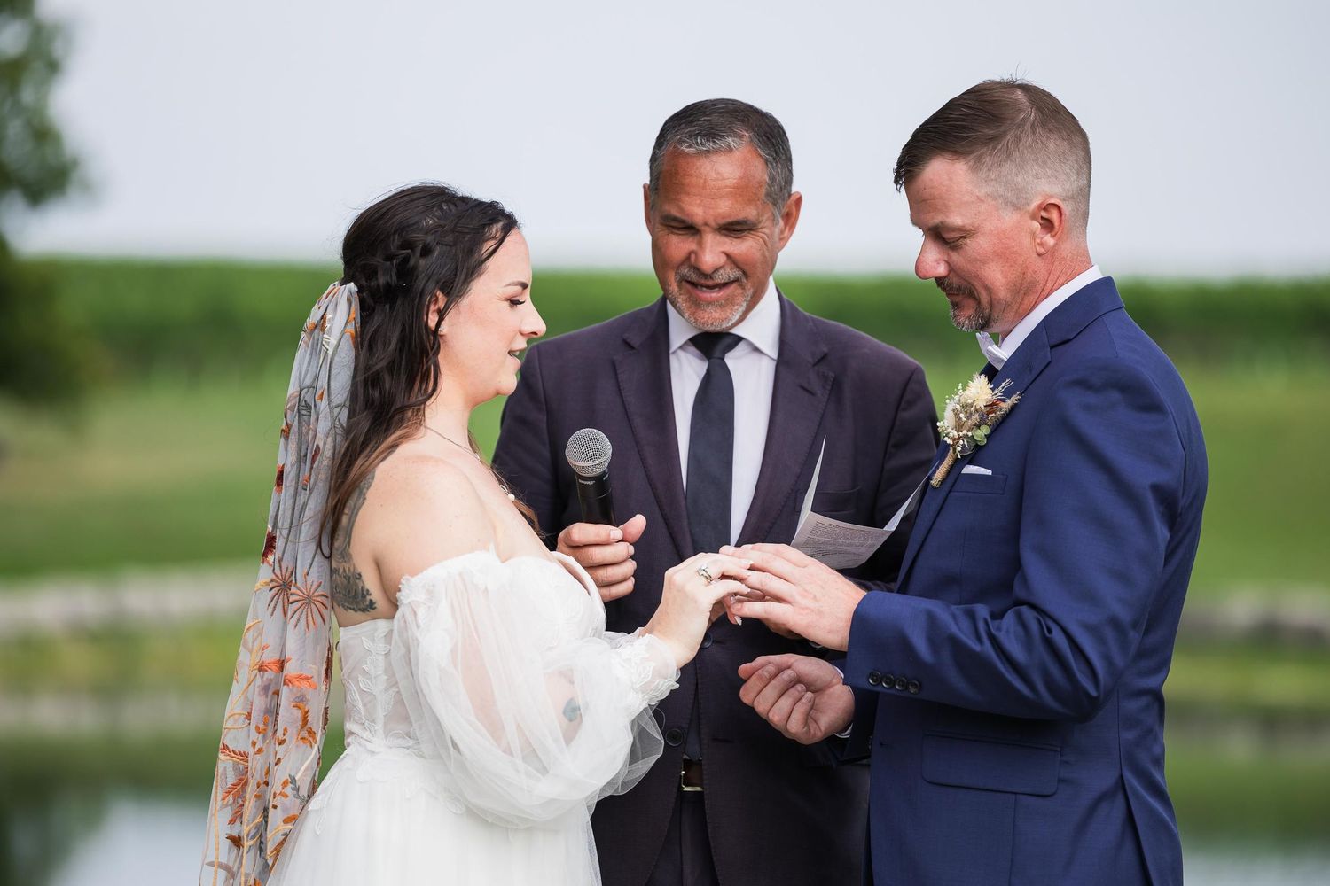 An emotional outdoor wedding ceremony moment captured against a serene lake backdrop.