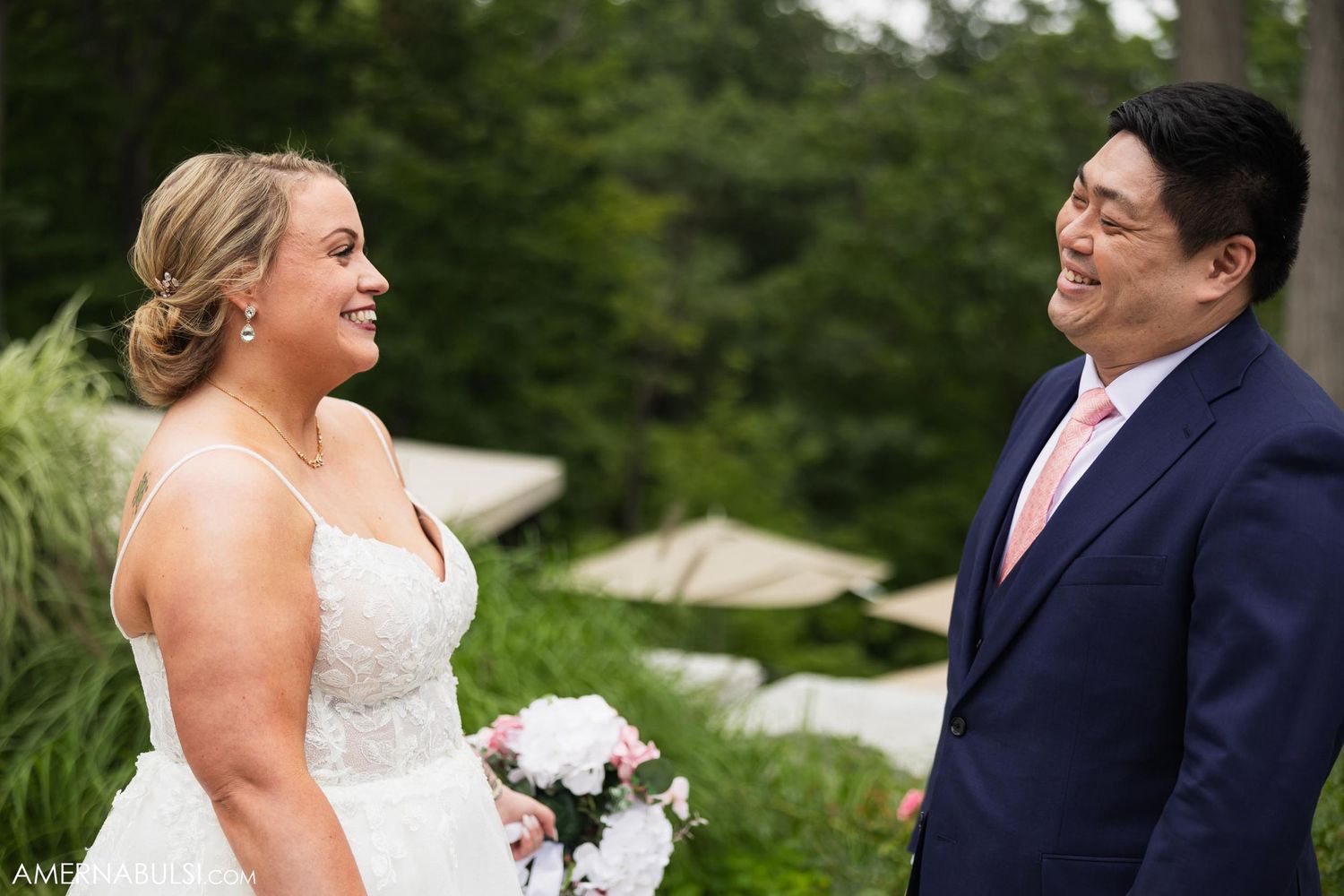 Couple shares a happy moment during their first look in a garden setting.