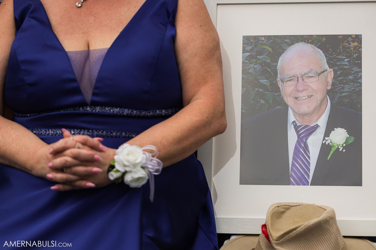 Detail shot of bridesmaid in navy dress with corsage next to framed portrait.